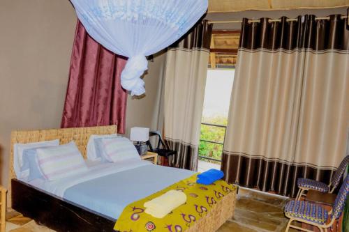 a bedroom with a bed and two chairs and a window at Palm garden Resort in Gisenyi