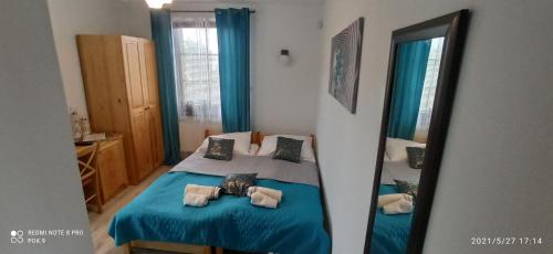 a bedroom with a blue bed and a mirror at Apartamenty Puk Puk in Mrągowo