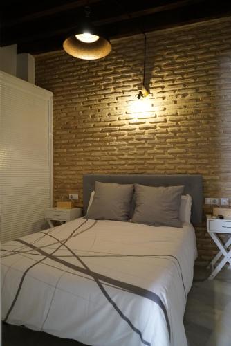 a bedroom with a large bed with a brick wall at Balcón Giralda Center & Sweet in Seville