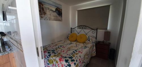 Un dormitorio con una cama con almohadas amarillas. en La Casita, en Playa de San Juan