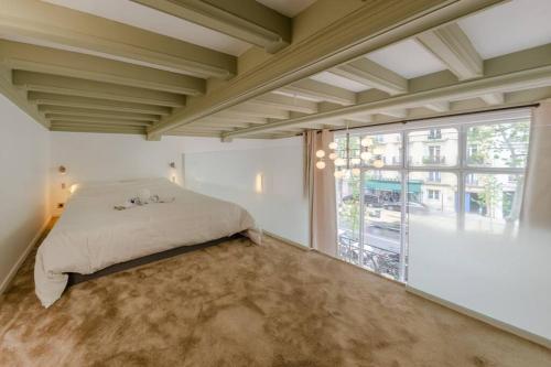 ein Schlafzimmer mit einem Bett und einem großen Fenster in der Unterkunft Appartement de standing 3 - tour Eiffel/Invalides in Paris