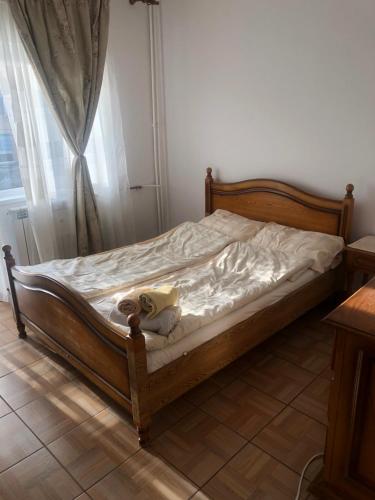 a bed with a wooden frame in a room with a window at Apartament Kiseleff in Drobeta-Turnu Severin