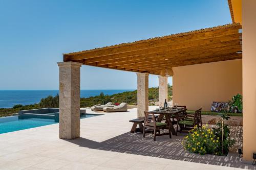 un patio con mesa y sillas junto a una piscina en Terra Lucis Mountain Residences en Agios Leon