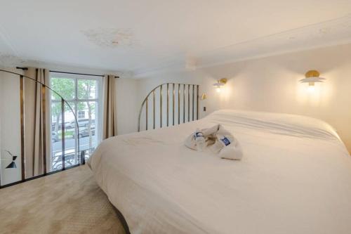 une chambre avec un grand lit blanc et un balcon dans l'établissement Appartement de standing 4 - tour Eiffel/Invalides, à Paris