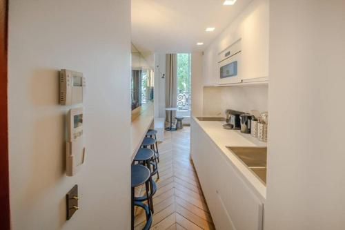 une cuisine avec comptoirs et tabourets blancs dans l'établissement Appartement de standing 4 - tour Eiffel/Invalides, à Paris