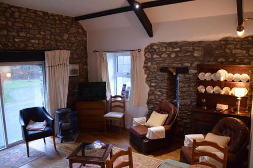 a living room with chairs and a stone wall at Fferm Y Felin in Carmarthen