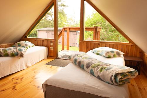 a attic room with two beds and a large window at Kempings ĒRGĻI in Bernāti