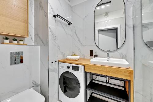 a bathroom with a washing machine and a mirror at Apartament Wałowa Shipyard Gdańsk in Gdańsk