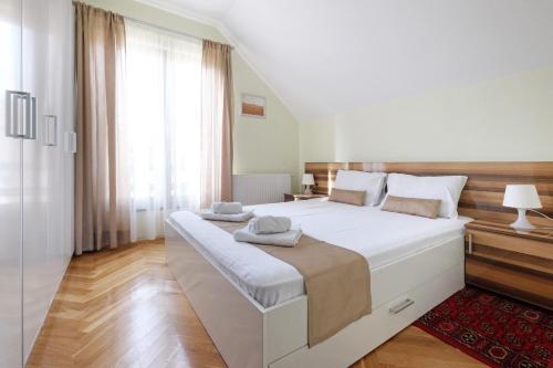 um quarto com uma grande cama branca com lençóis brancos em Apartments Bohemia em Zlatibor