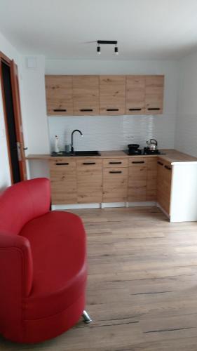 a living room with a red chair and a kitchen at SORKWITY- Pensjonat - STARY GIELĄD in Sorkwity