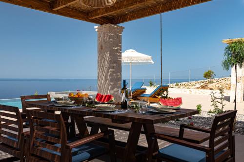 a wooden table with chairs on a patio with the ocean at Terra Lucis Mountain Residences in Agios Leon