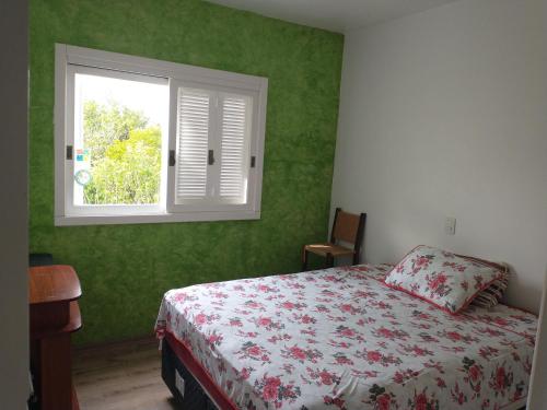 a bedroom with green walls and a bed and a window at Casa da tranquilidade in Bento Gonçalves
