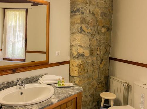 a bathroom with a sink and a stone wall at Posada Las Espedillas in Camaleño