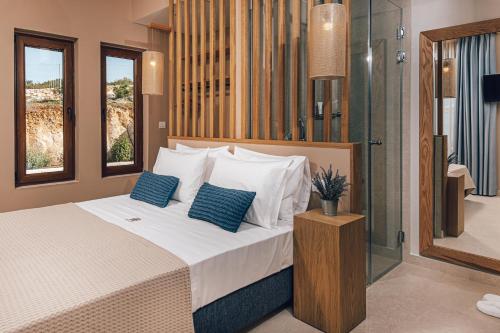 a bedroom with a bed with blue pillows at Terra Lucis Mountain Residences in Agios Leon