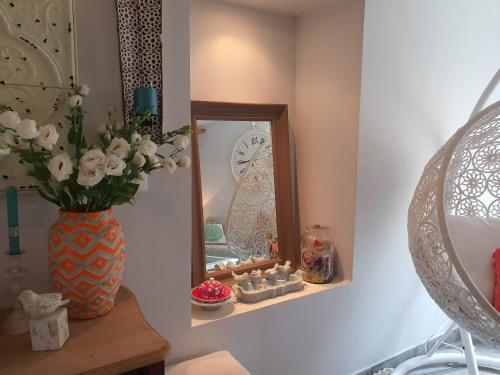 un vase de fleurs sur une table à côté d'un miroir dans l'établissement Traverse du Vieux Château, à Menton