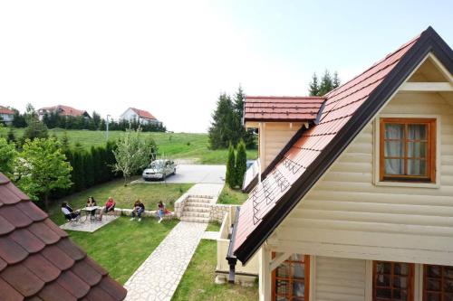 a house with a red roof and a wooden bench in front of it at Apartments Bohemia in Zlatibor