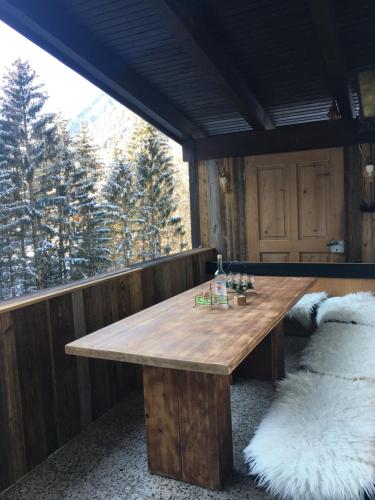 a wooden table on a balcony with a view of the mountains at Bike 'n' Board Lodge Brandnertal in Brand