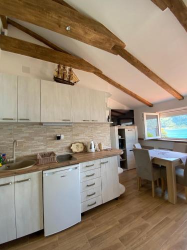 a kitchen with white cabinets and a dining table at Sunny Bay Apartments in Kotor