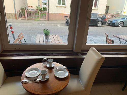 a table with two cups and saucers on it next to a window at Hafner Hotel Apartment Self Check-In Anytime in Stuttgart