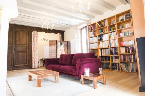 uma sala de estar com um sofá roxo e estantes em Le Pressoir chambres d'hôtes em Cardaillac