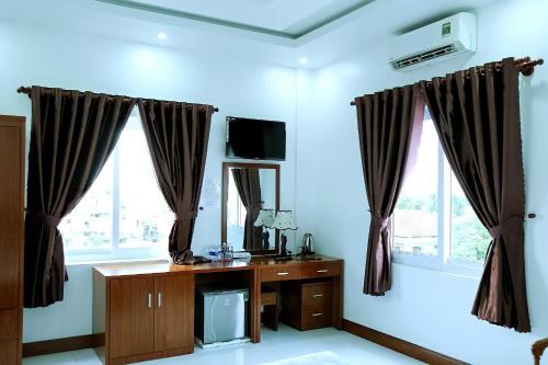 a room with a desk and two windows at HOTEL ĐĂNG KHOA 1 NÚI SAM in Chau Doc