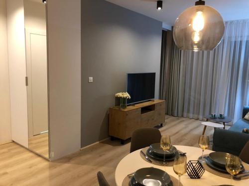 a living room with two tables and a television at Apartament Kameleon in Dźwirzyno
