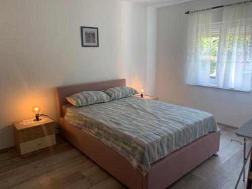 a bedroom with a bed and two lamps on a night stand at Apartman Dalija in Vinkuran