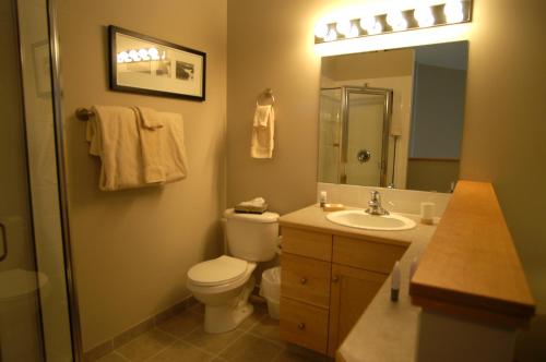 a bathroom with a toilet and a sink and a mirror at Apartment 407, Contemporary Decor in Canmore