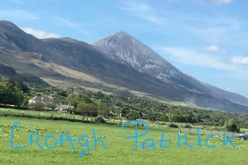 a sign in a field with mountains in the background at Annies Meadow. in Knock