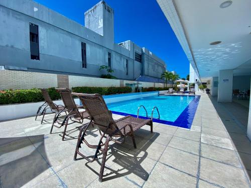 a group of chairs sitting next to a swimming pool at Nobile Suítes Tambaú in João Pessoa