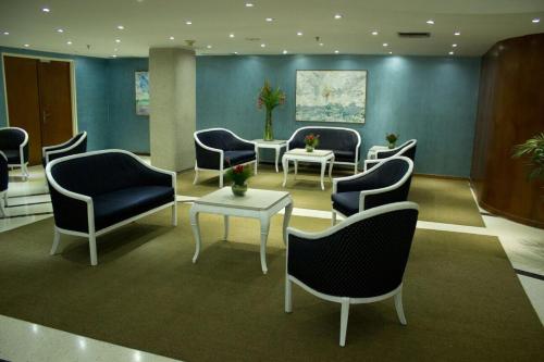 a waiting room with blue chairs and tables at Hotel Chacao Cumberland in Caracas