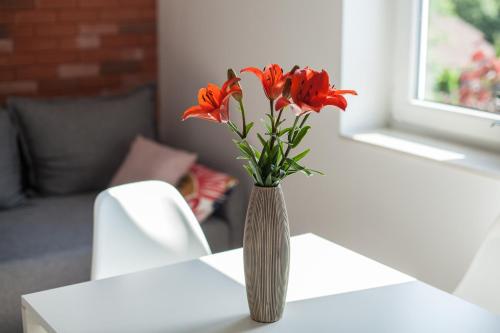 a vase with red flowers sitting on a table at Lawendowo- sauna, basen, domki w ogrodzie i apartamenty w kamienicy in Sandomierz