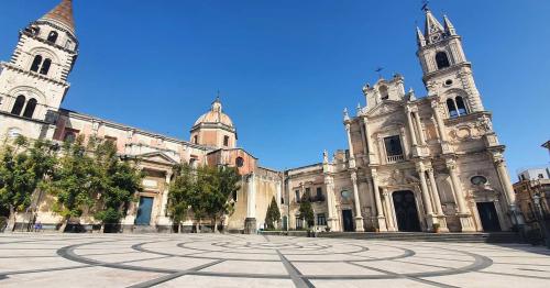 a cathedral with a clock in the middle of a courtyard at Antica Dimora Barocca in Acireale