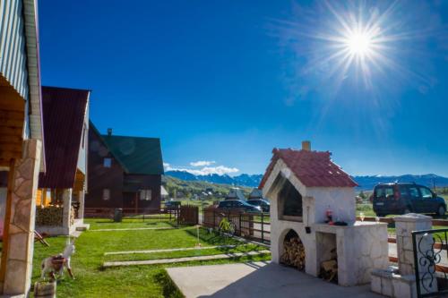 a dog house in a yard with the sun in the sky at Village Borje in Žabljak