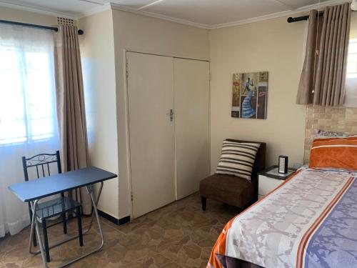 1 dormitorio con 1 cama, 1 mesa y 1 silla en Furnished self-catering bedsitter, en Lusaka
