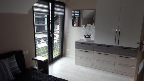 a bedroom with a dresser and a large window at Comfort Villa in Pobierowo