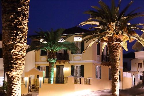 two palm trees in front of a building at night at Nostos Hotel in Galaxidi