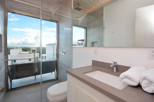 a bathroom with a sink and a toilet and a window at MAYAN MONK Suites in Playa del Carmen