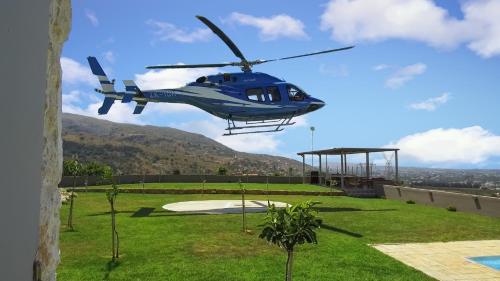 un hélicoptère bleu survole une cour dans l'établissement Villa Kedria with a panoramic ocean view, à Souda