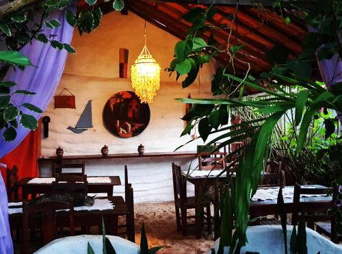 un restaurante con mesas y sillas y una lámpara de araña en Pousada JeriMagia en Jericoacoara