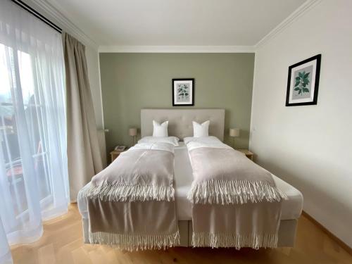 a bedroom with a bed with white sheets and a window at Boutique Hotel Aichinger in Nussdorf am Attersee