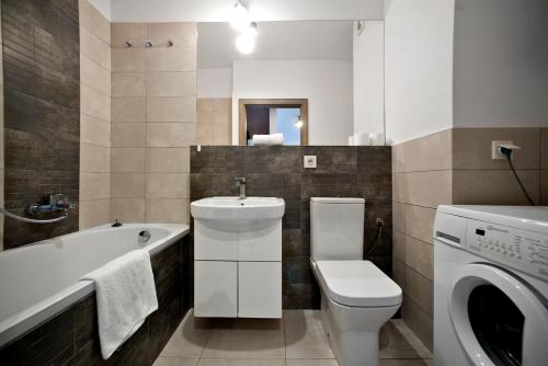 a bathroom with a toilet sink and a washing machine at Airport Okecie Klobucka P&O Serviced Apartments in Warsaw