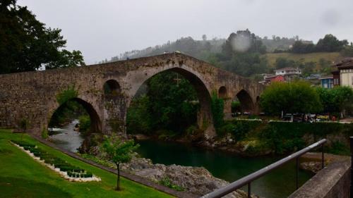 an old stone bridge over a river in a town at Apartamento Casa Geli #1 in La Robellada de Onis