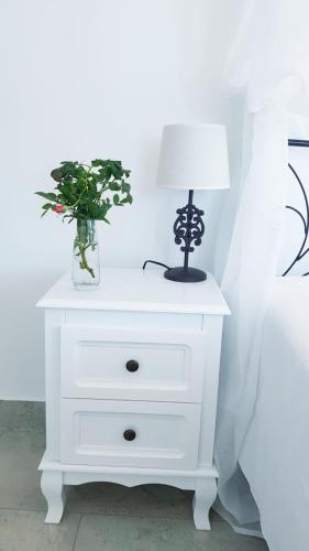 a white nightstand with a lamp and a vase of flowers at Dimora Brezza di Mare in Termoli