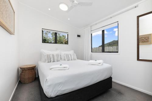 a white bedroom with a large bed with white sheets at Bowentown Beach Holiday Park in Waihi Beach