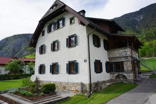 a white house with black windows and a mountain at Apartment Haider 2 in Obertraun