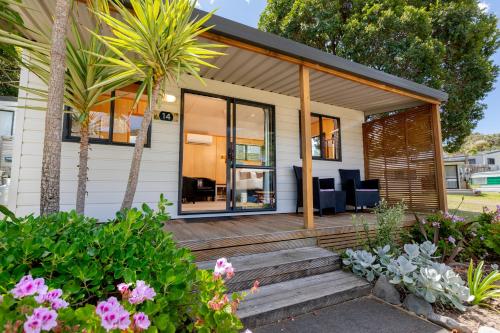 a home with a porch and deck with flowers at Bowentown Beach Holiday Park in Waihi Beach