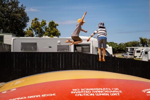 two people jumping on top of a trampoline at Bowentown Beach Holiday Park in Waihi Beach