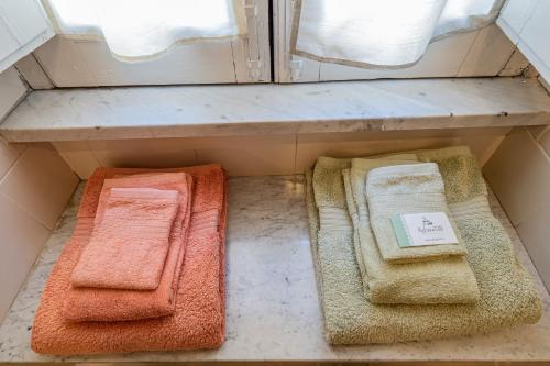 cuatro toallas de diferentes colores sentadas en un estante en Agliata 138, en Petralia Sottana