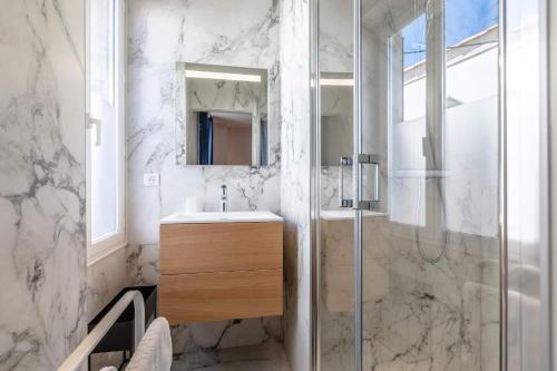 une salle de bain avec un lavabo et une douche avec un miroir dans l'établissement Biarritz Beaurivage, à Biarritz